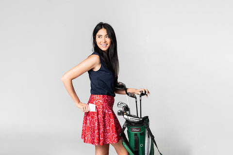woman wearing red emyvale skirt holding golf bag