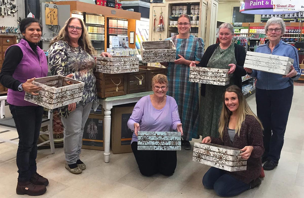7 women holding decorated apple crates