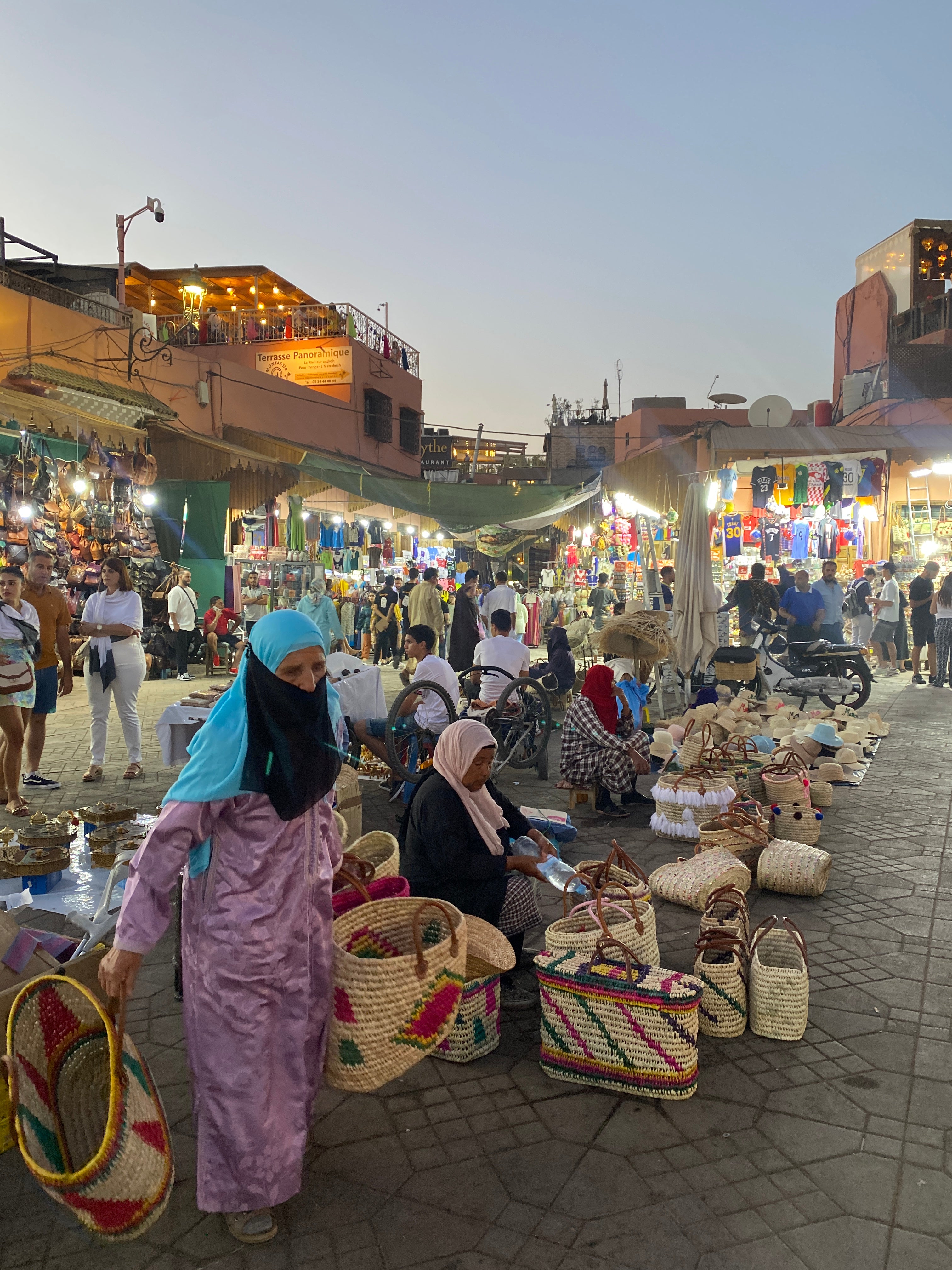 Marrakech Medina at dusk with traders, entertainment, and shopping in full swing.