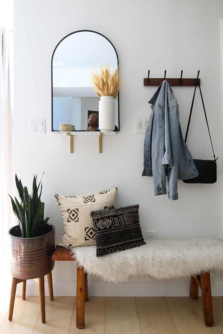 Entryway delineated by small, slender bench and wall-mounted organization solutions