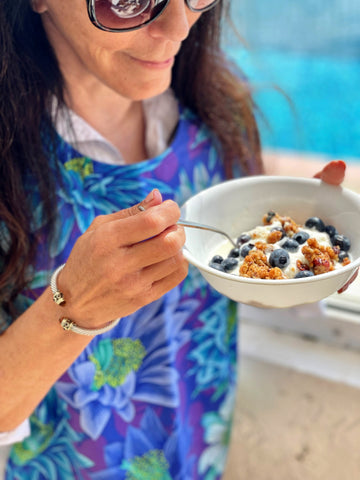 Woman eating breakfast wearing BAVETTE adult bib in Purple Passion