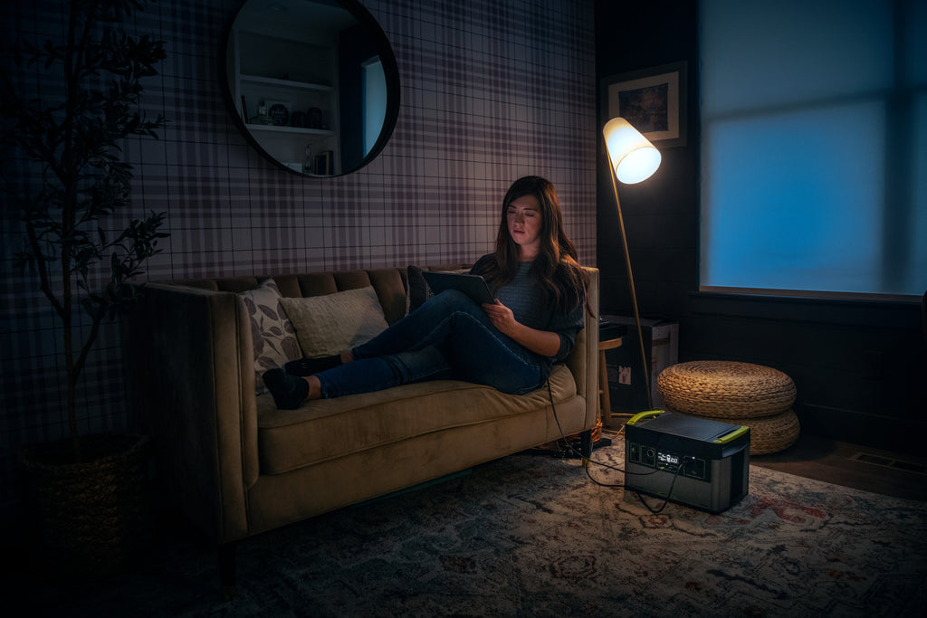 Goal Zero Yeti Portable Power Station powering a tablet being used by a woman sitting on a couch in a living room.