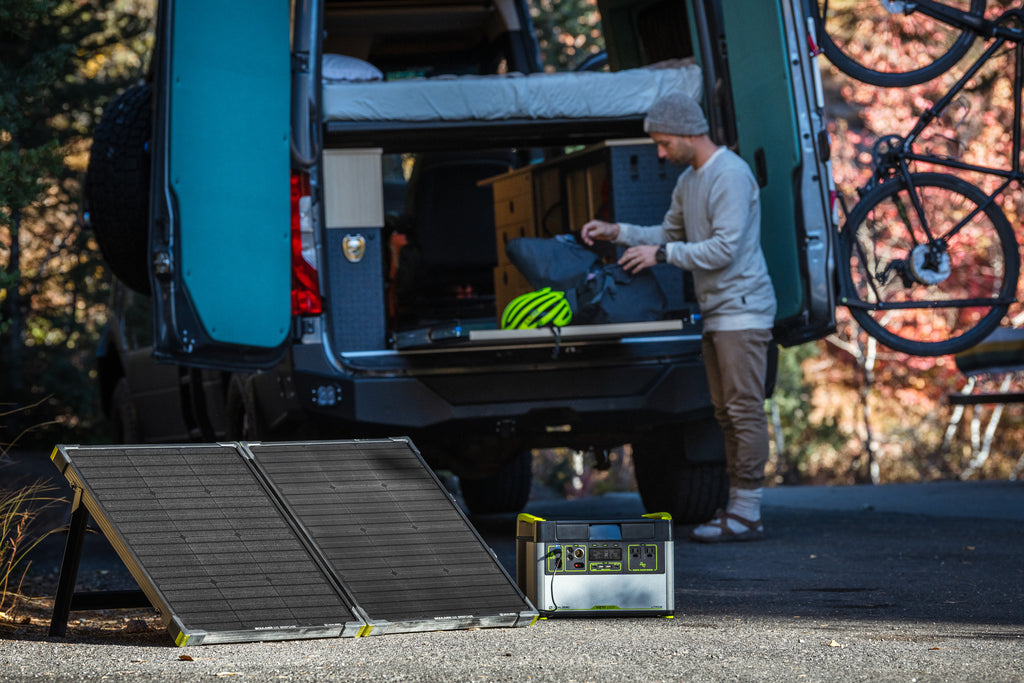 Goal Zero Yeti Portable Power Station + Boulder Solar Panel Solar Generator Kit being used outdoors with a van and a mountain bike in the background.
