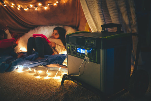 A child relaxes in a blanket fort with lights that are powered by a Goal Zero power station.