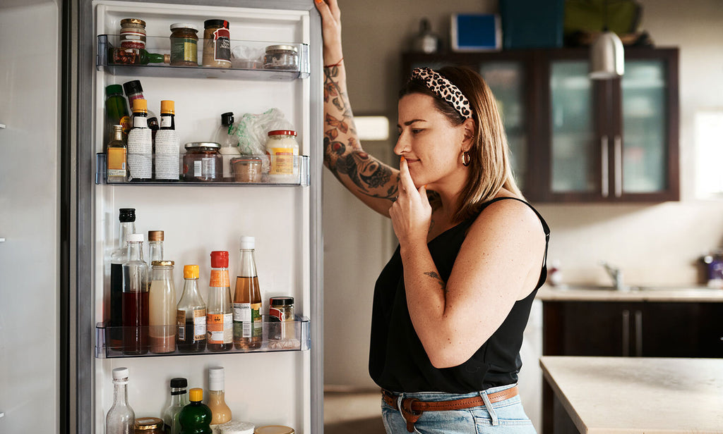 Woman thinking in front of an open refrigerator during a power outage