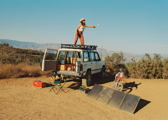 Someone stands on top of a van near a portable solar generator
