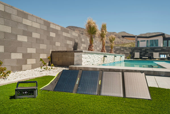 Des panneaux Goal Zero sont installés sur une pelouse à côté d'une piscine pendant le chargement d'une centrale électrique