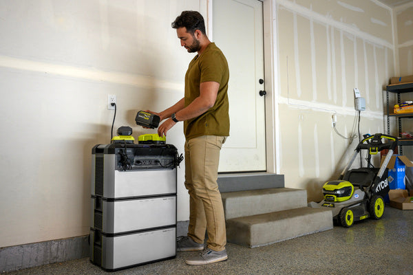 A man stands next to a Yeti PRO 4000 with two Tank PRO 4000 expansion batteries stacked beneath the Yeti.