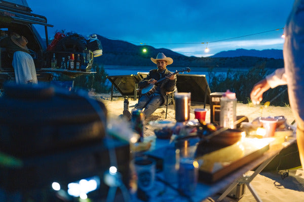 Someone sits at a campsite and plays music. 