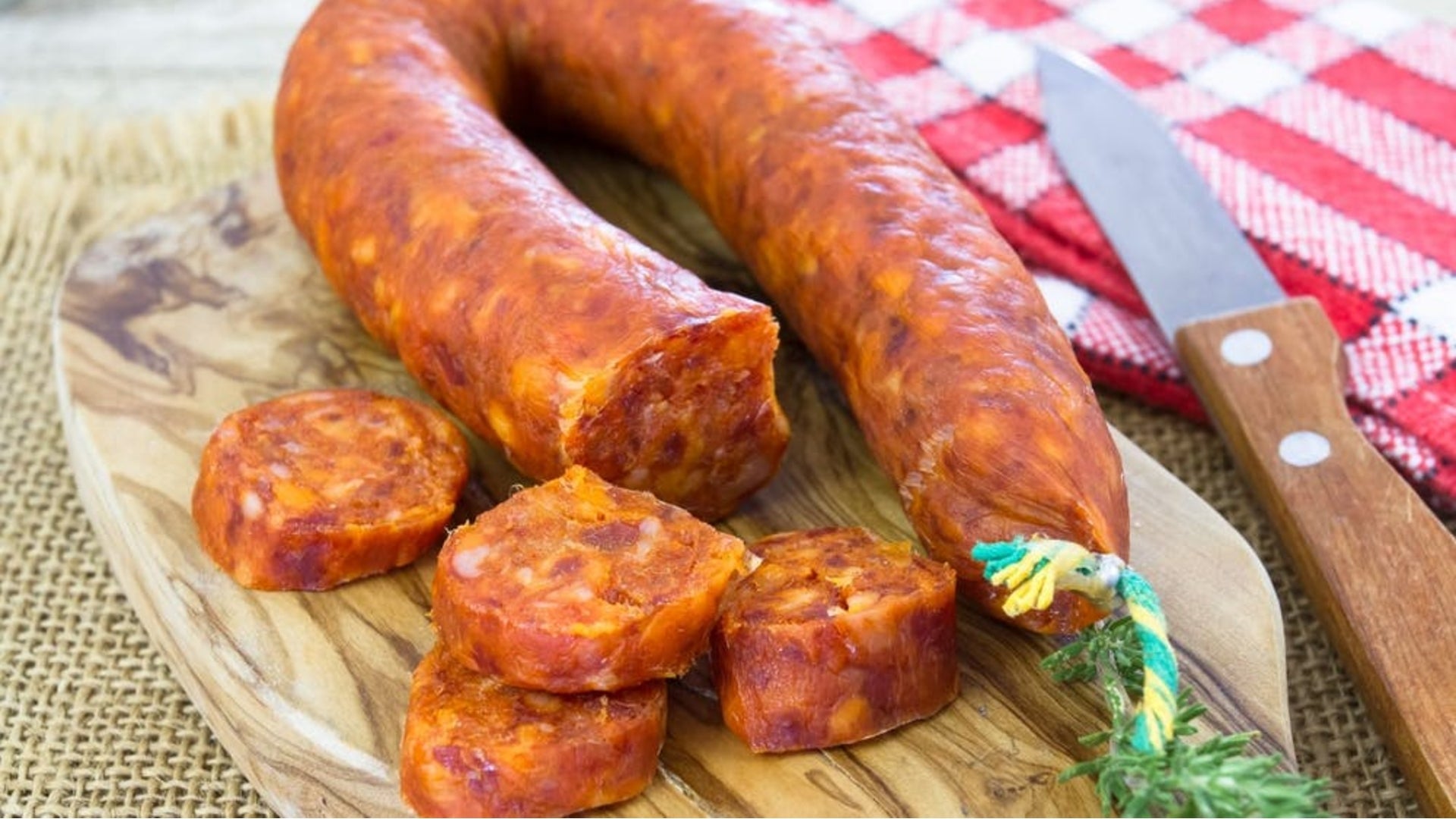 Chorizo sausage on a cutting board with several slices cut in the foreground.