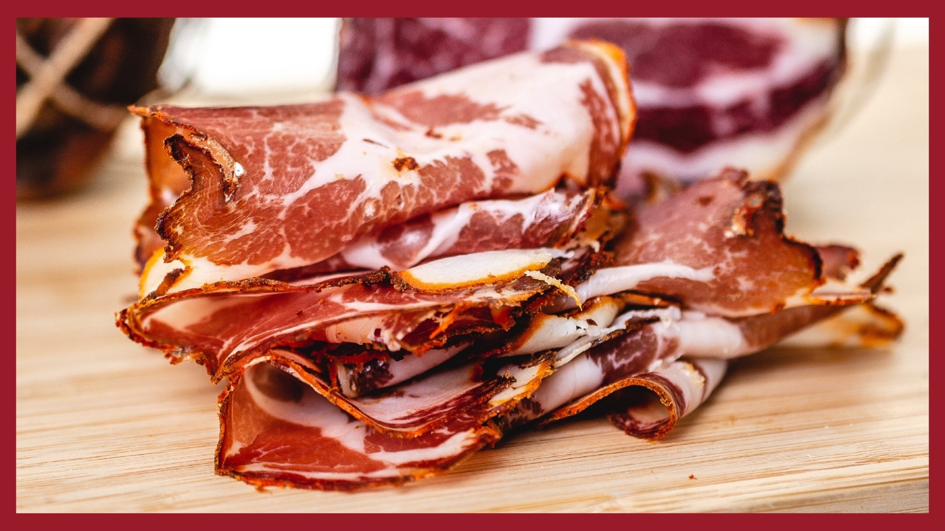 A stack of thinly sliced coppa on a cutting board.