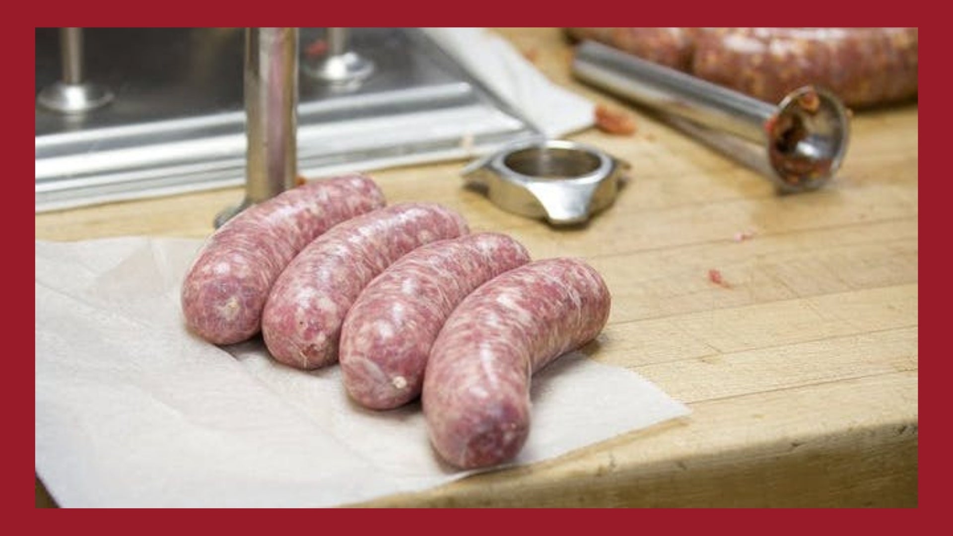 Fresh bratwursts on a butchers table with sausage stuffing equipment in the background.