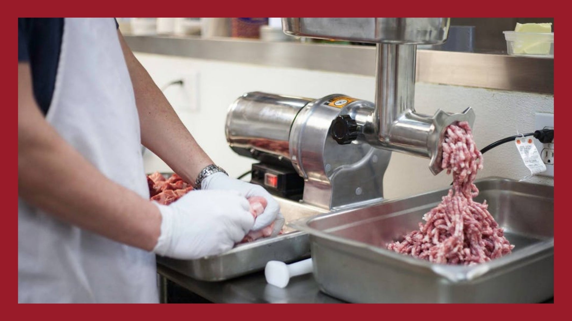 Pork meat and fat coming out of a grinder and landing in a container.