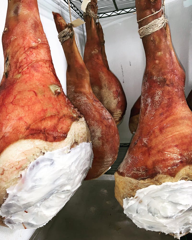 Country hams hanging in the dry room during the dry curing process.