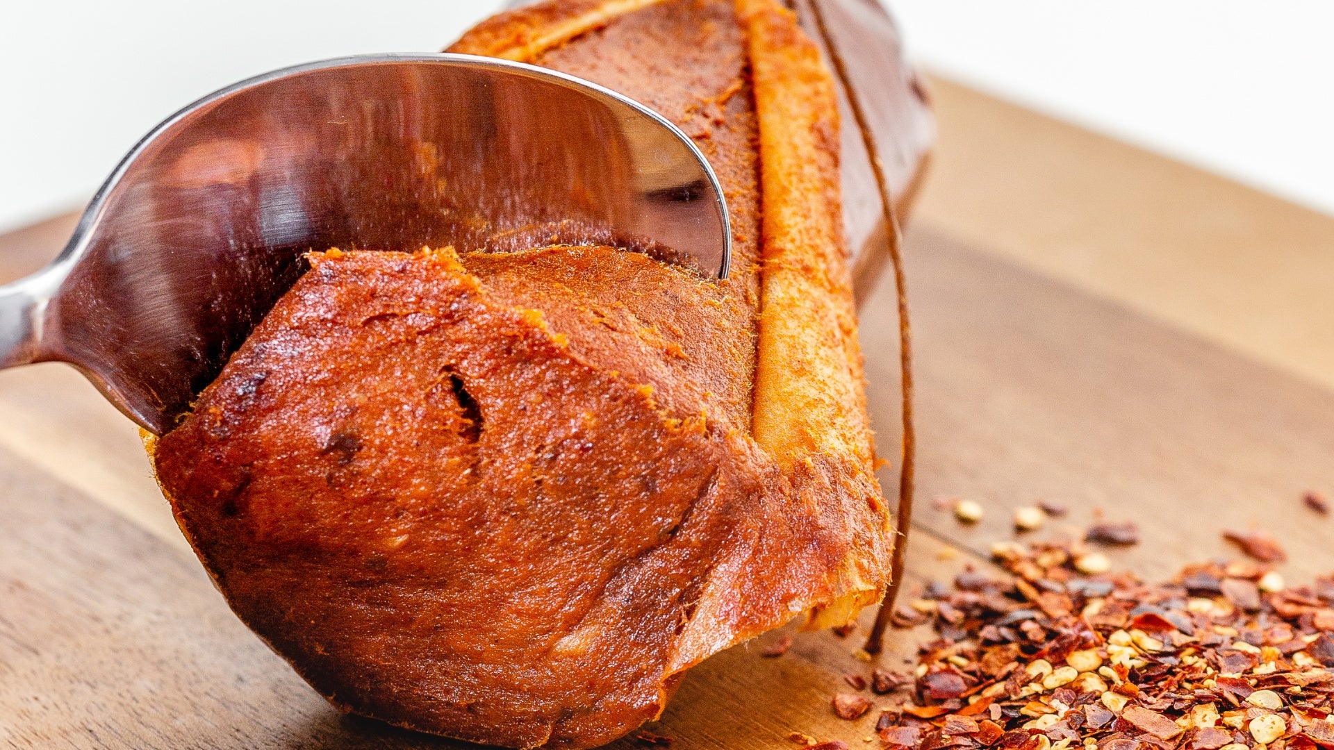 A close up of 'Nduja salami on a cutting board cut into with a spoon to show that 'nduja is soft and spreadable.