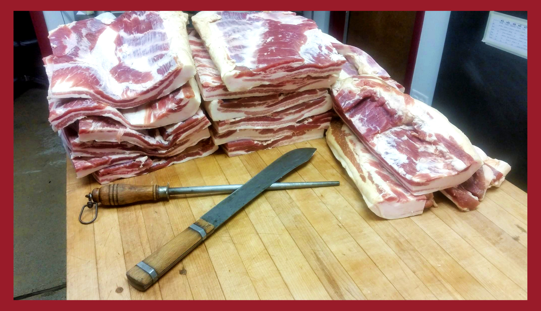 Several stacks of pork bellies on a butcher table before they're prepared for dry curing to make bacon.