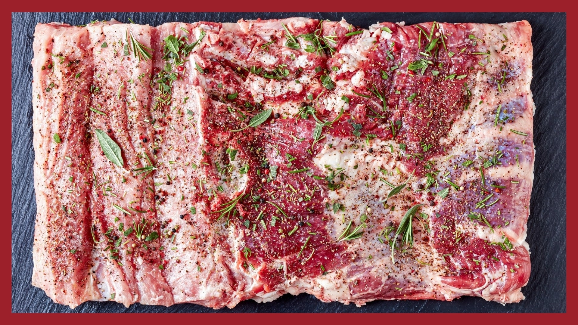 A whole pork belly covered with herbs and spices before it is rolled and tied to make porchetta. 