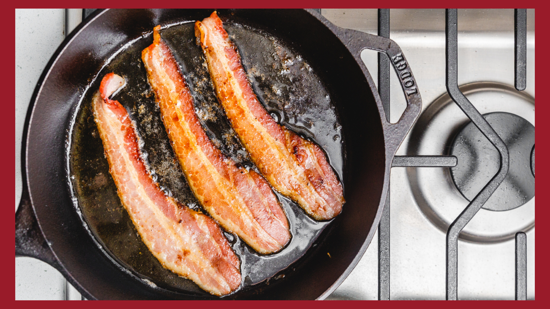 A picture looking down at three strips of bacon cooking in a cast iron skillet on a gas stove.