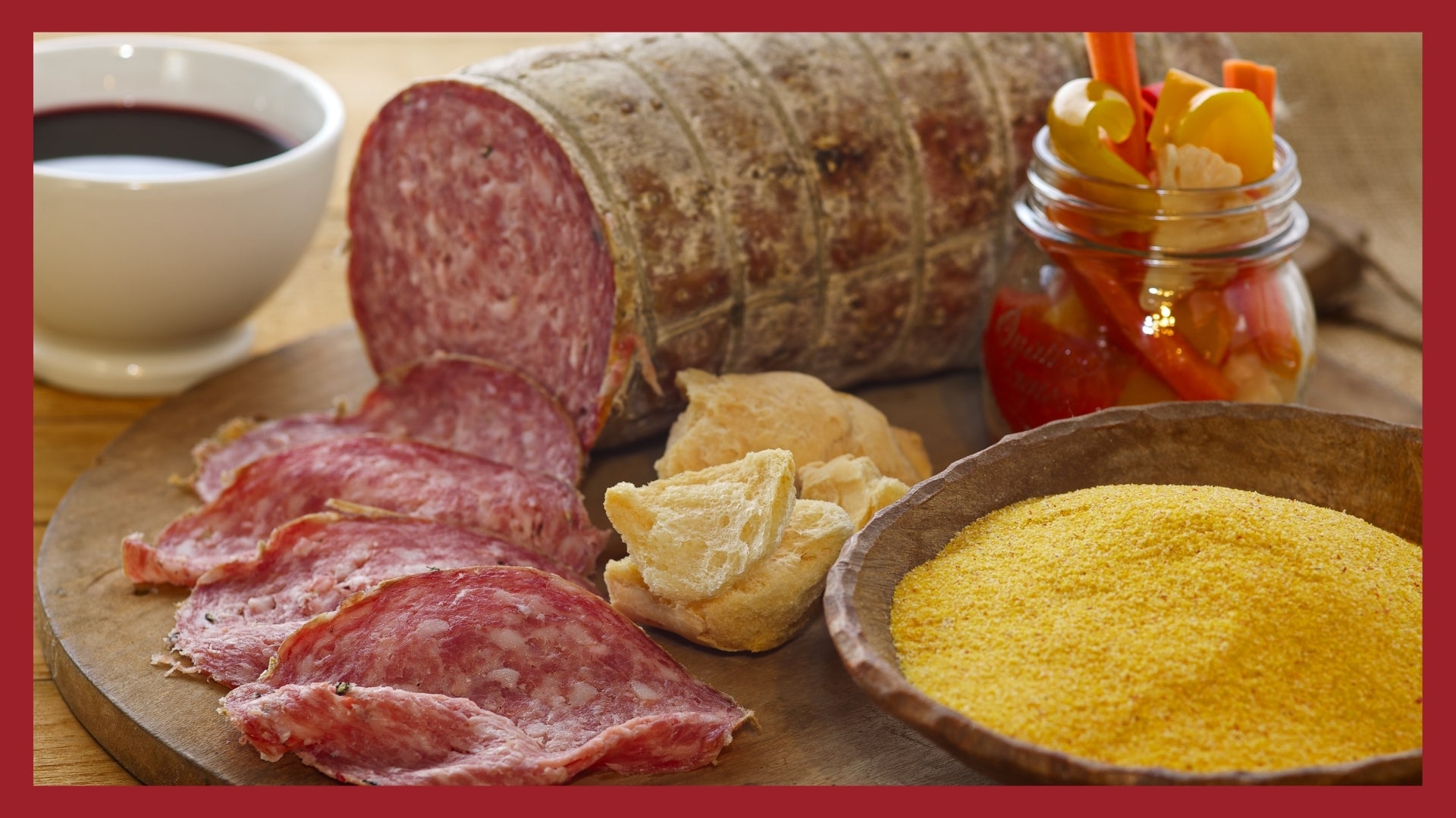 Sopressa on a cutting board with slices and ingredients in the foreground.