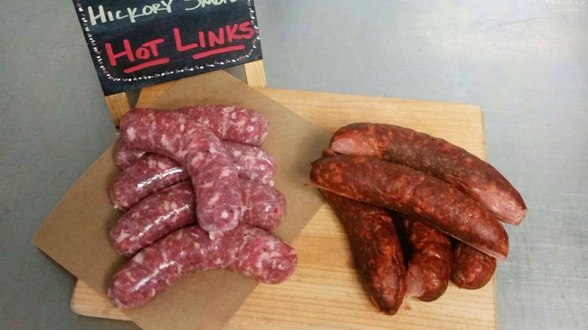 A picture showing several fresh and smoked sausages side by side on a cutting board to show the difference between the two types of sausages.