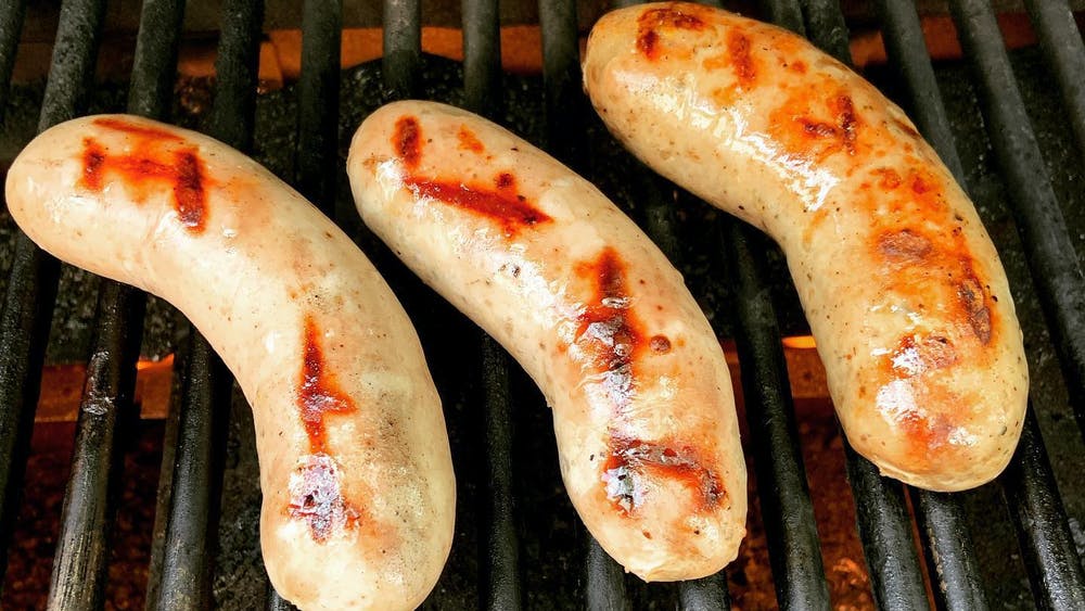 Three sausages being grilled.
