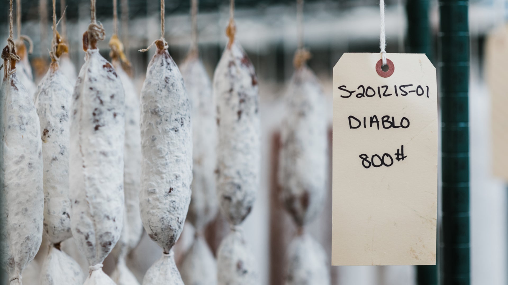 A picture showing hanging salami with a thick coat of good mold to protect the meat from spoiling.