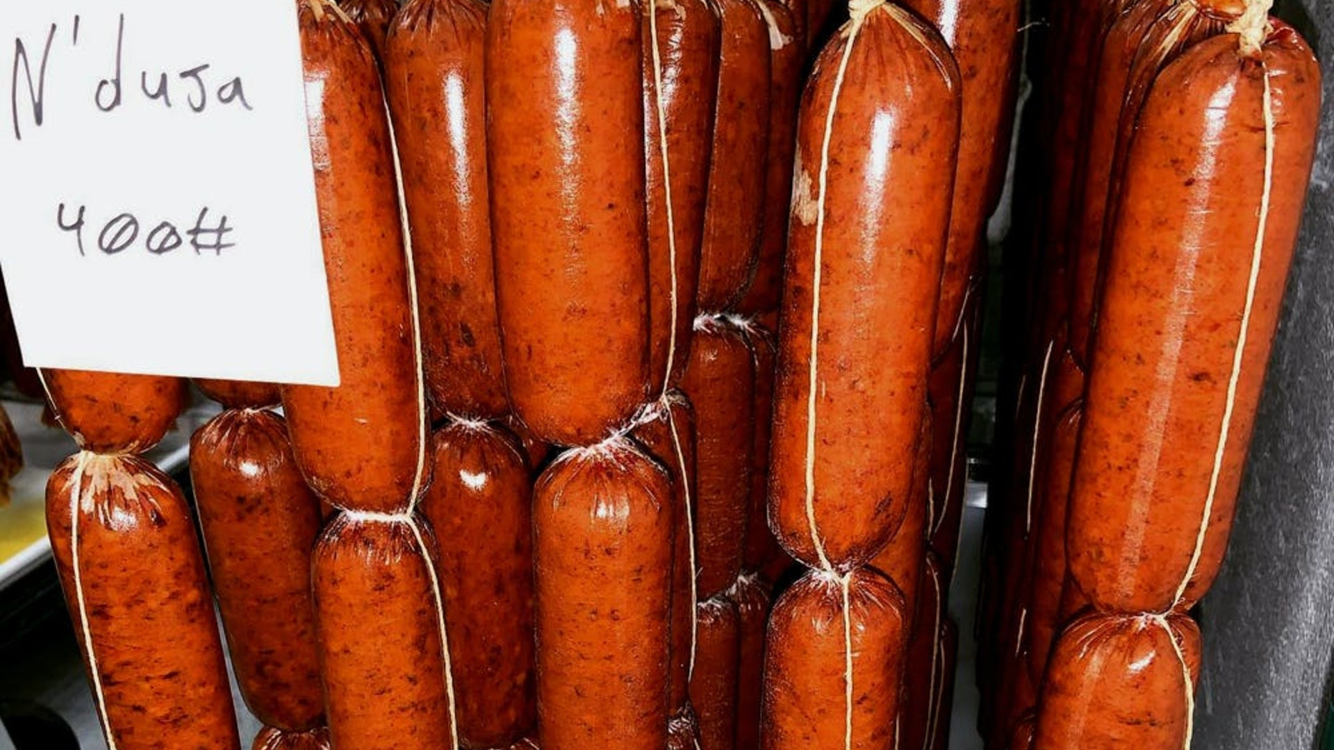 A close up of 'Nduja chubs hanging in the fermentation room.