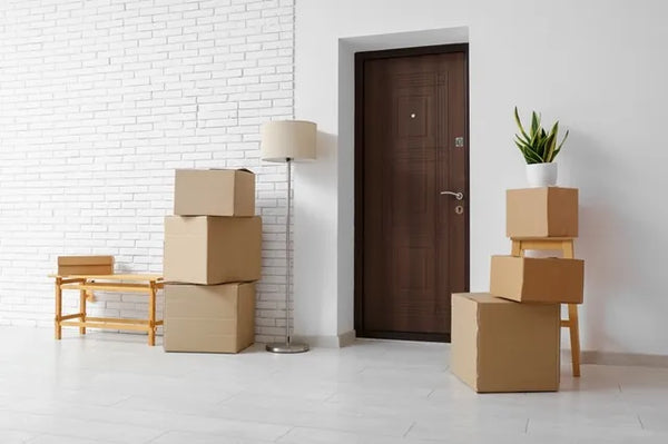 Cardboard boxes with floor lamp near door in room