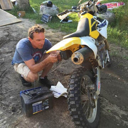 OmegaStrap founder Brad Willodson attending to a repair on a dirt bike.