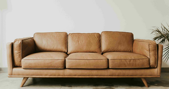 Sofá de piel marrón de tres plazas en salón de estilo minimalista