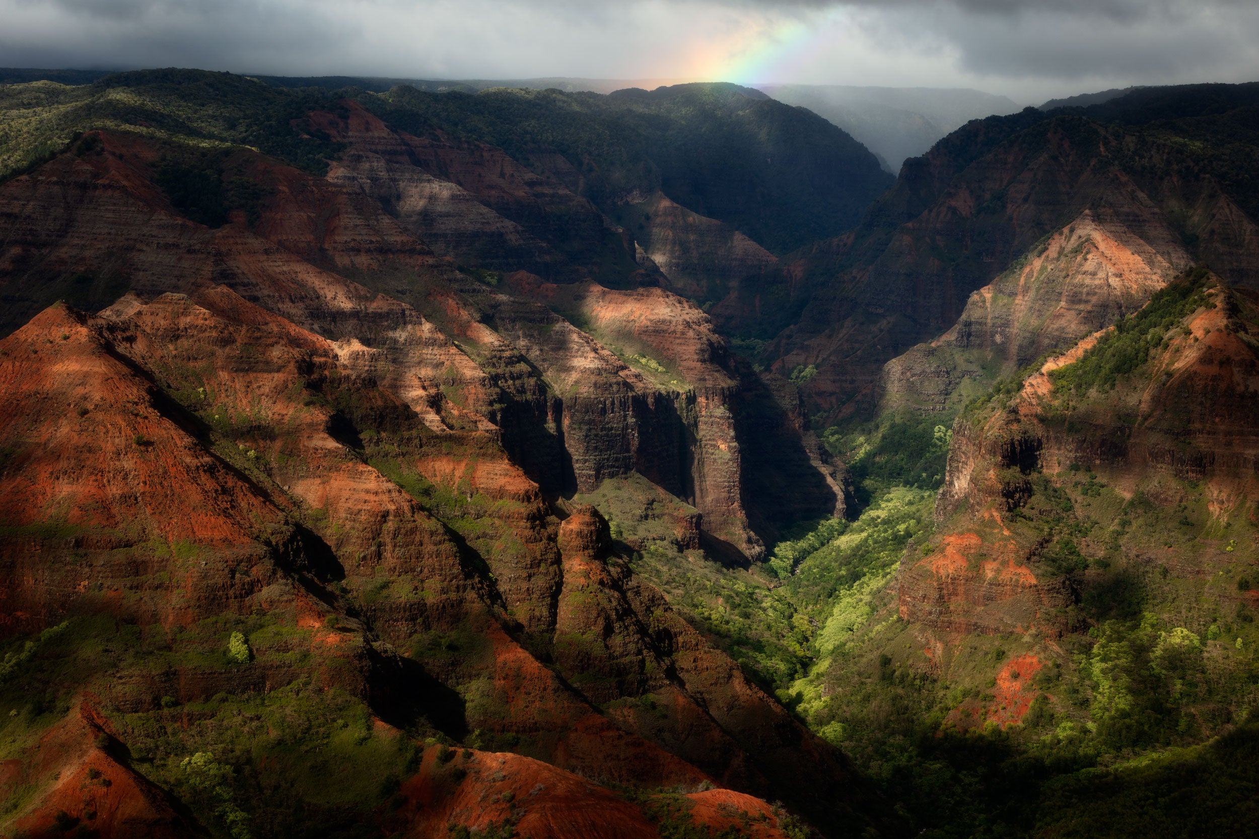 A Lars Gesing fine art nature photograph of a rainbow over Waimea Canyon on the island of Kauai, Hawaii. Waimea canyon is easy to get to by road and is nicknamed The Grand Canyon of the Pacific.