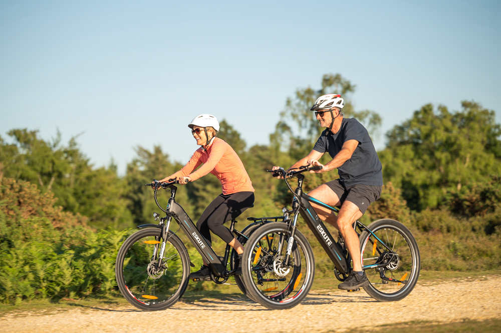 A man and a woman riding an electric bike on the highway