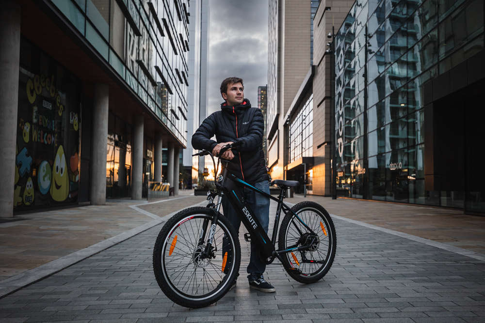 A man stands on the street and holds his commuter e-bike