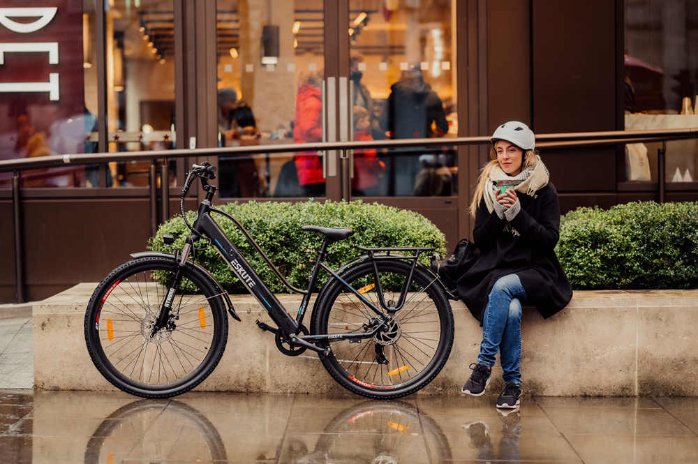 a lady with a white helmet parks the wayfarer commute e-bike for a rest