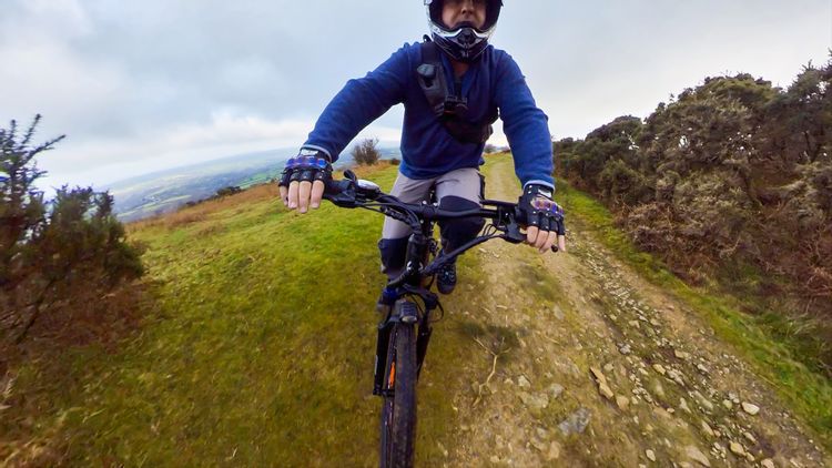 a man with full-face MTB helmet is riding electric mountain bike 
