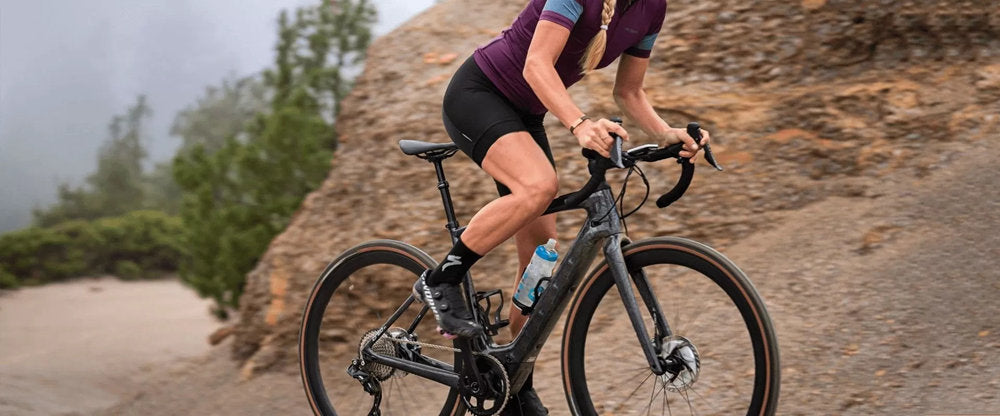 a woman rides electric road bike going up steep hills