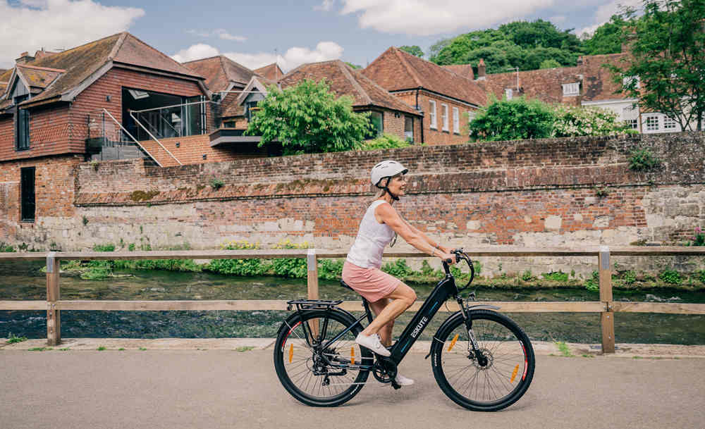 a woman with a helmet rides an e-bike on the country road