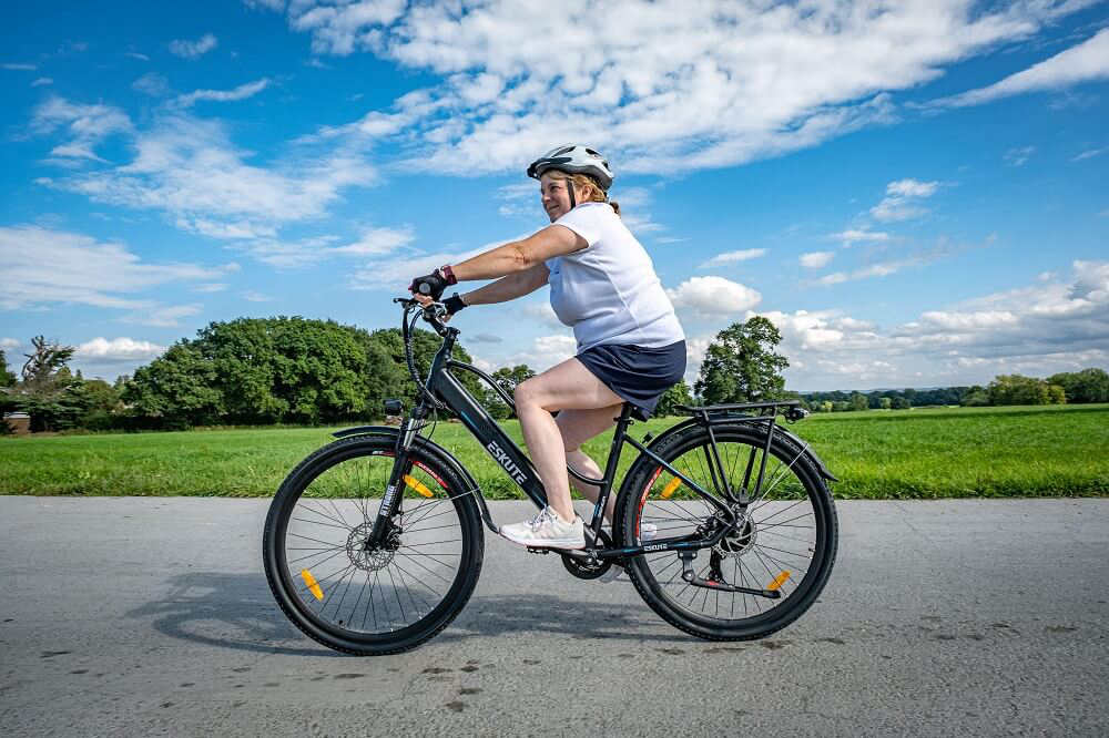 a woman with helmet is riding her electric push bike on the road