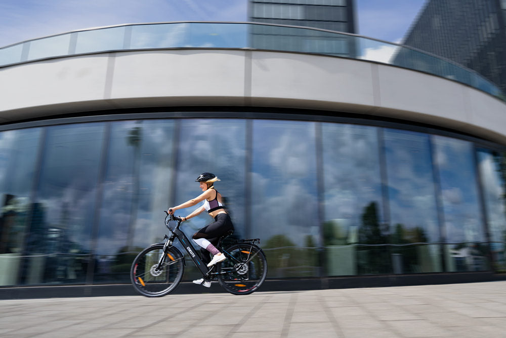 a young lady rides an e-bike fast around the round building