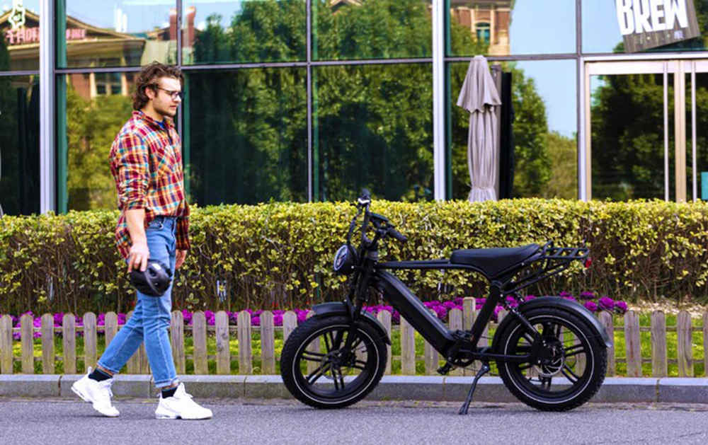 a young man walks to his fat tyre e-bike with the helmet in his hand