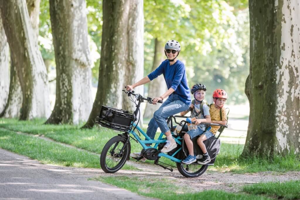 a young mother is riding the e-bike carrying her two children