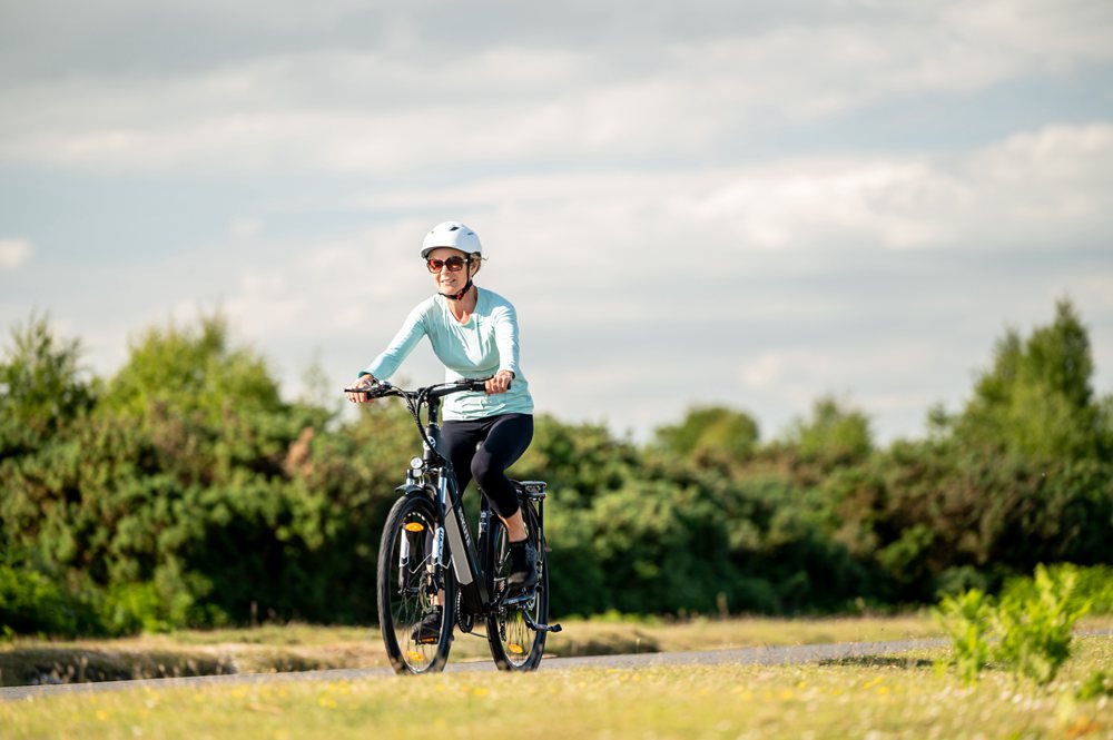 a lady with helmet is riding the electric cruiser bike in the grassland