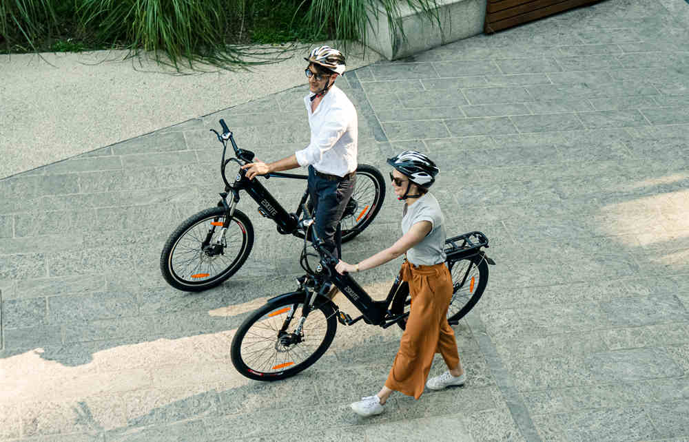 a man and a woman push their ebikes forward