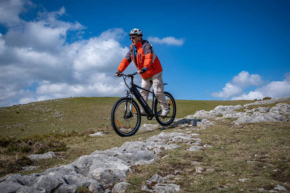 a man with helmet is riding netuno ebike on the mountain top 