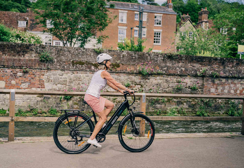 a woman in pink skirt is riding polluno e-bike on the road