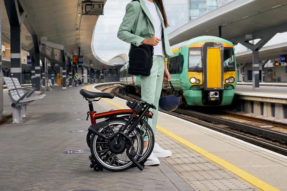 a woman is waiting for metro with her foldable ebike