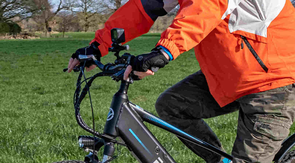 the male rider with cycling gloves holds the brake levers tightly on the e-bike