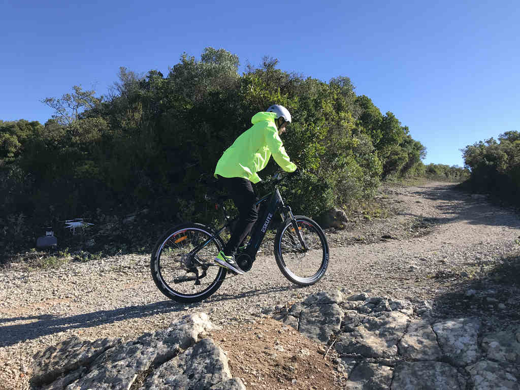 the rider in the yellow jacket pedals his e-bike hard on the uphill