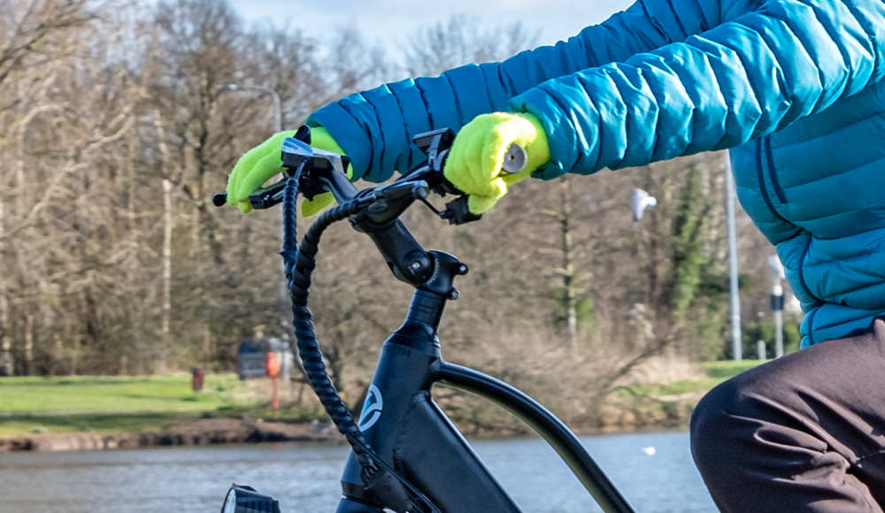 the rider with gloves holds the brake levers tightly on the e-bike