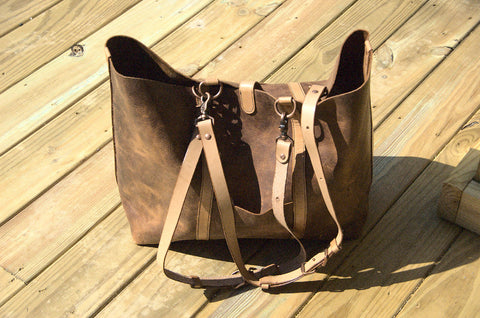 Wanderer shoulder bag with handles fully extended into shoulder straps. Chestnut brown pull-up distressed leather in the sun. 